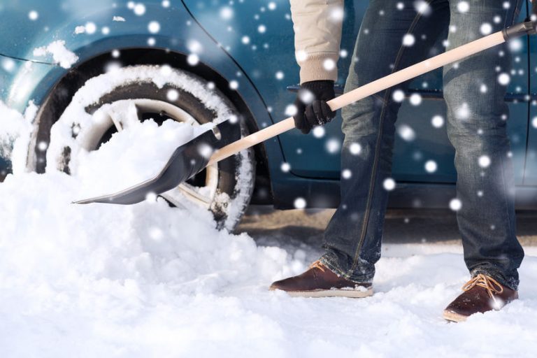 transportation, winter, people and vehicle concept - closeup of man digging snow with shovel near car