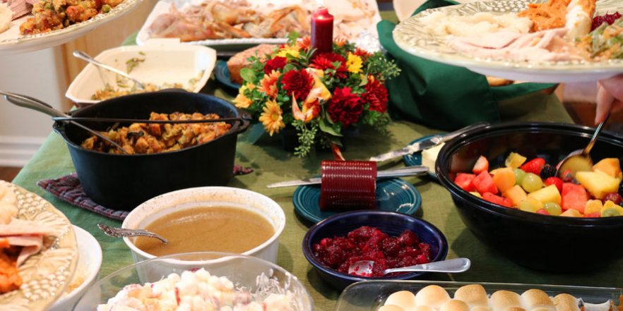 casual thanksgiving dinner on table with family filling plates