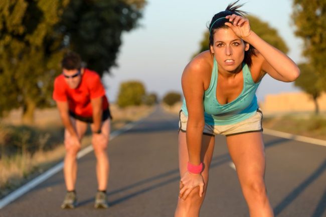 21976510_s tired fitness couple of runners sweating and taking a rest during marathon training in country road sweaty athletes after running hard