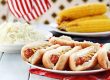 hotdogs with mustard, cole slaw and corn on a cob at a 4th of july bbq picnic.