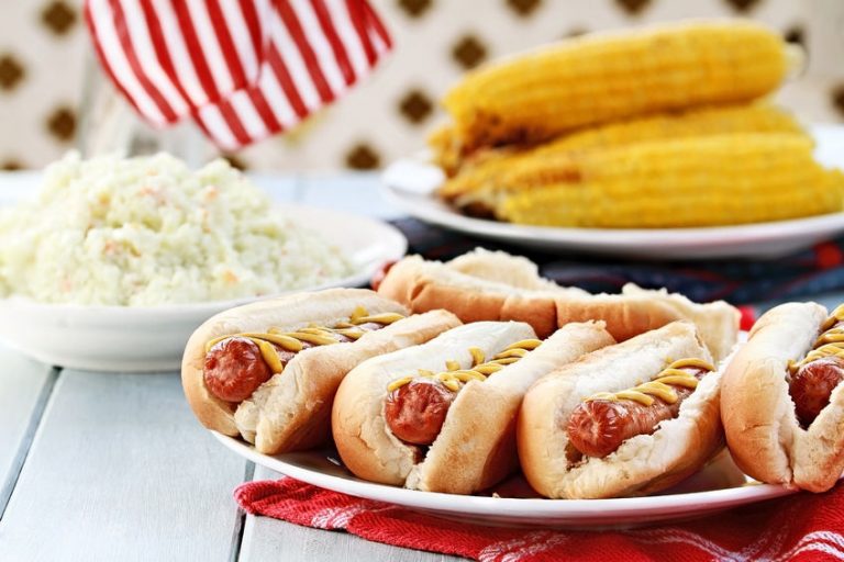 hotdogs with mustard, cole slaw and corn on a cob at a 4th of july bbq picnic.