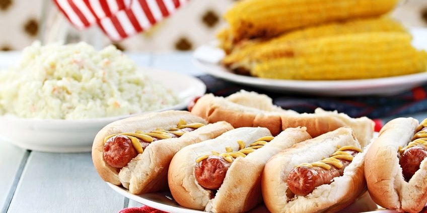 hotdogs with mustard, cole slaw and corn on a cob at a 4th of july bbq picnic.